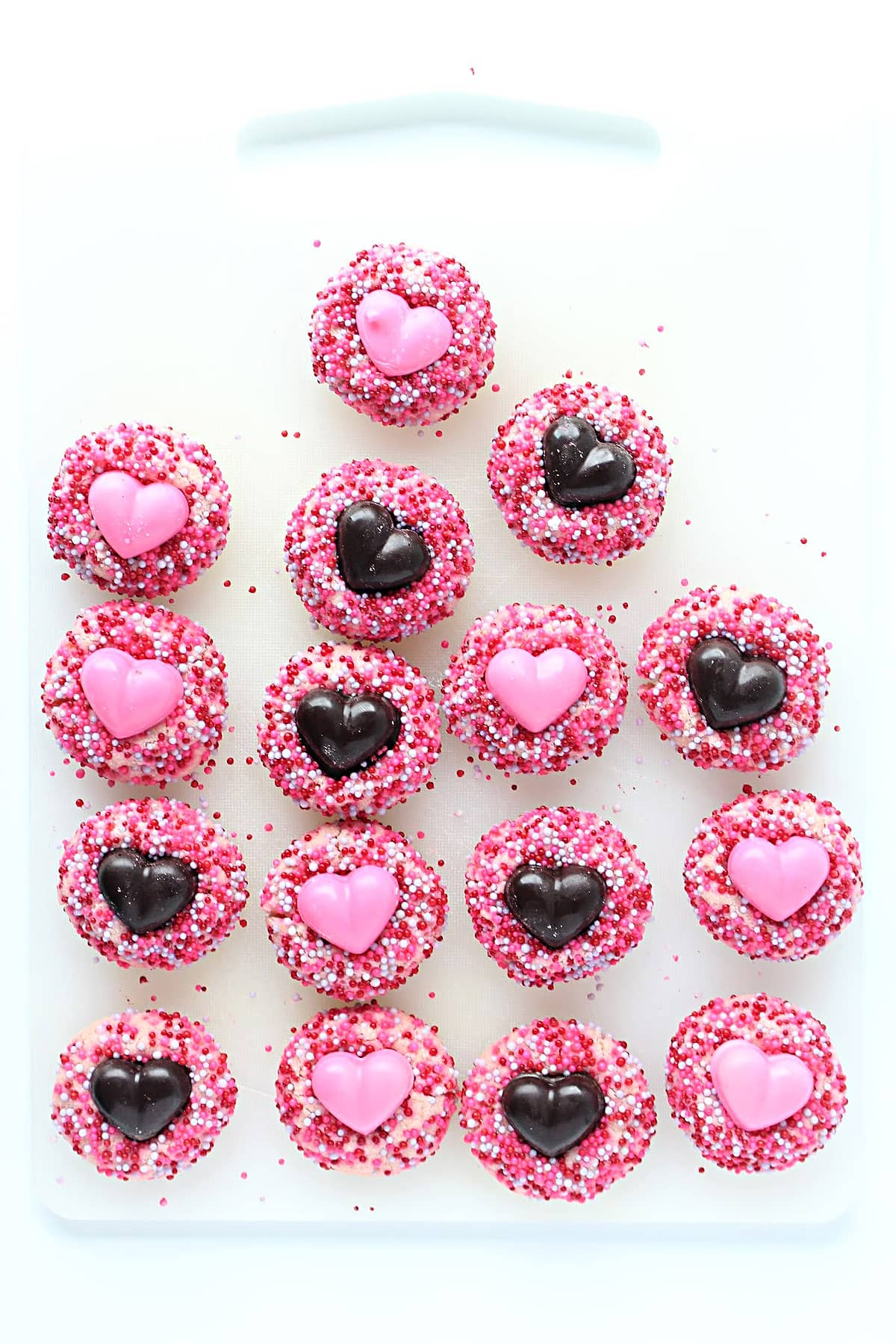 Round shortbread thumbprint cookies coated in nonpareil sprinkles with chocolate heart centers.