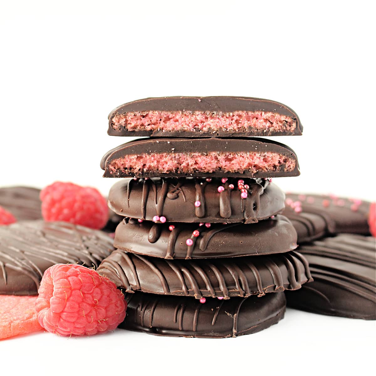 Stack of chocolate coated cookies with two cookie halves on top showing pink cookie inside.