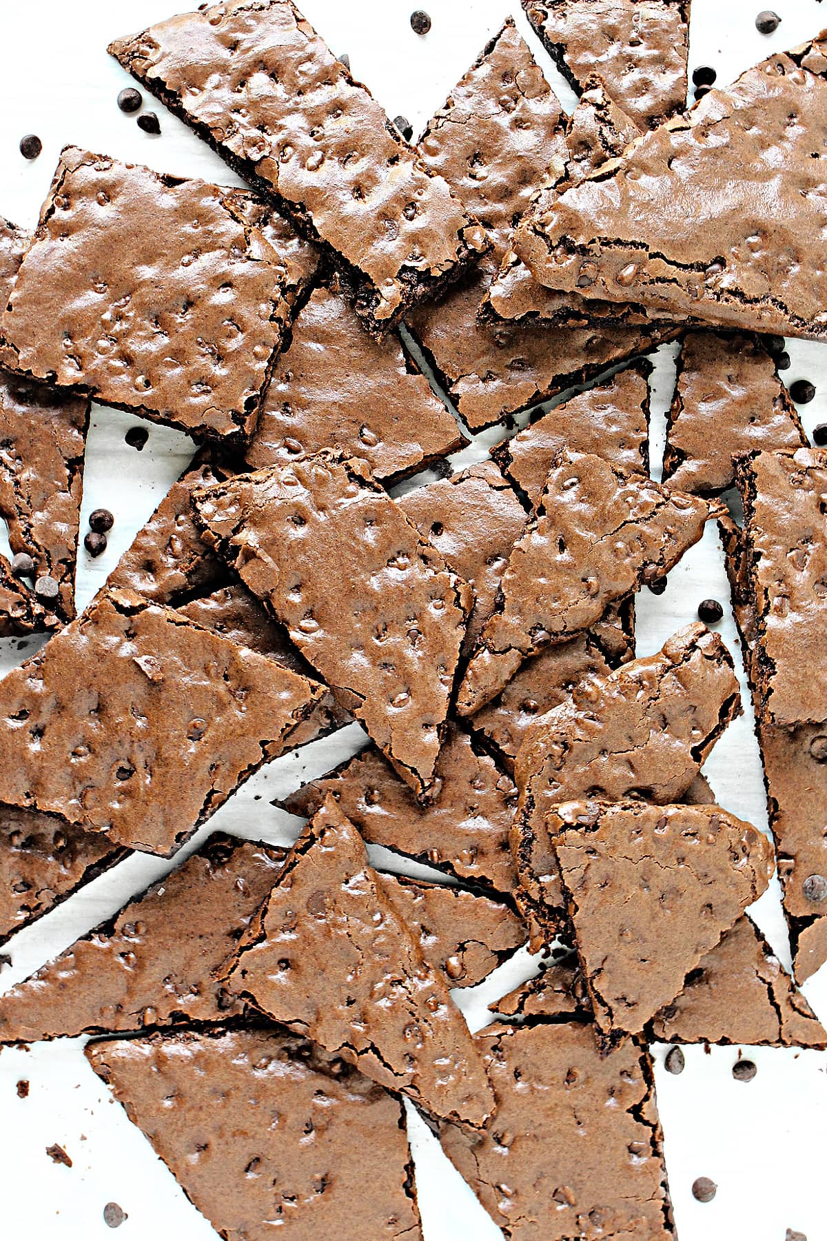 Various shaped wedges of thin, brownie brittle with shiny, chocolate chip speckled tops.
