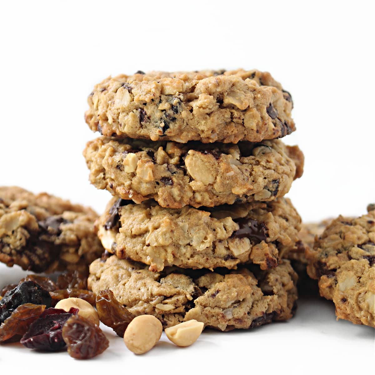 Stack of thick oatmeal cookies with bits of fruit, chocolate and peanuts.