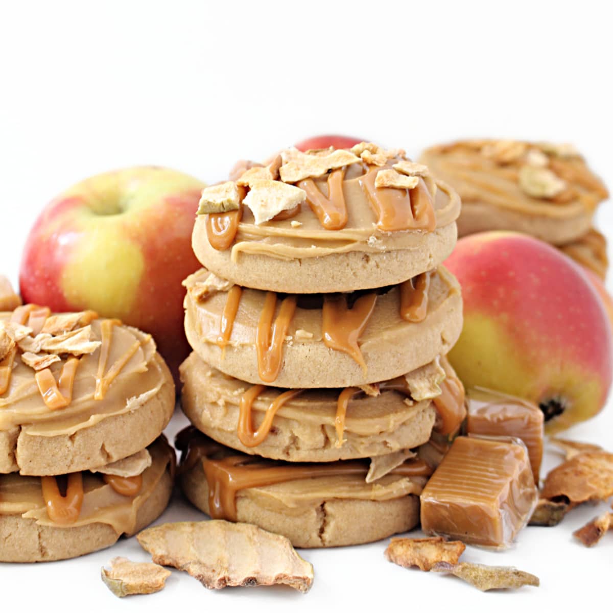 Stack of thick, frosted apple butter cookies drizzled with melted caramel candies and apple chips.