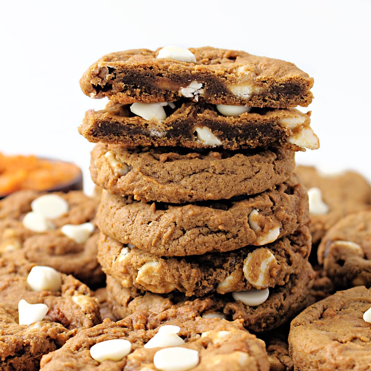 Stack of pumpkin cookies with cut open cookie on top showing dense, chewy interior.