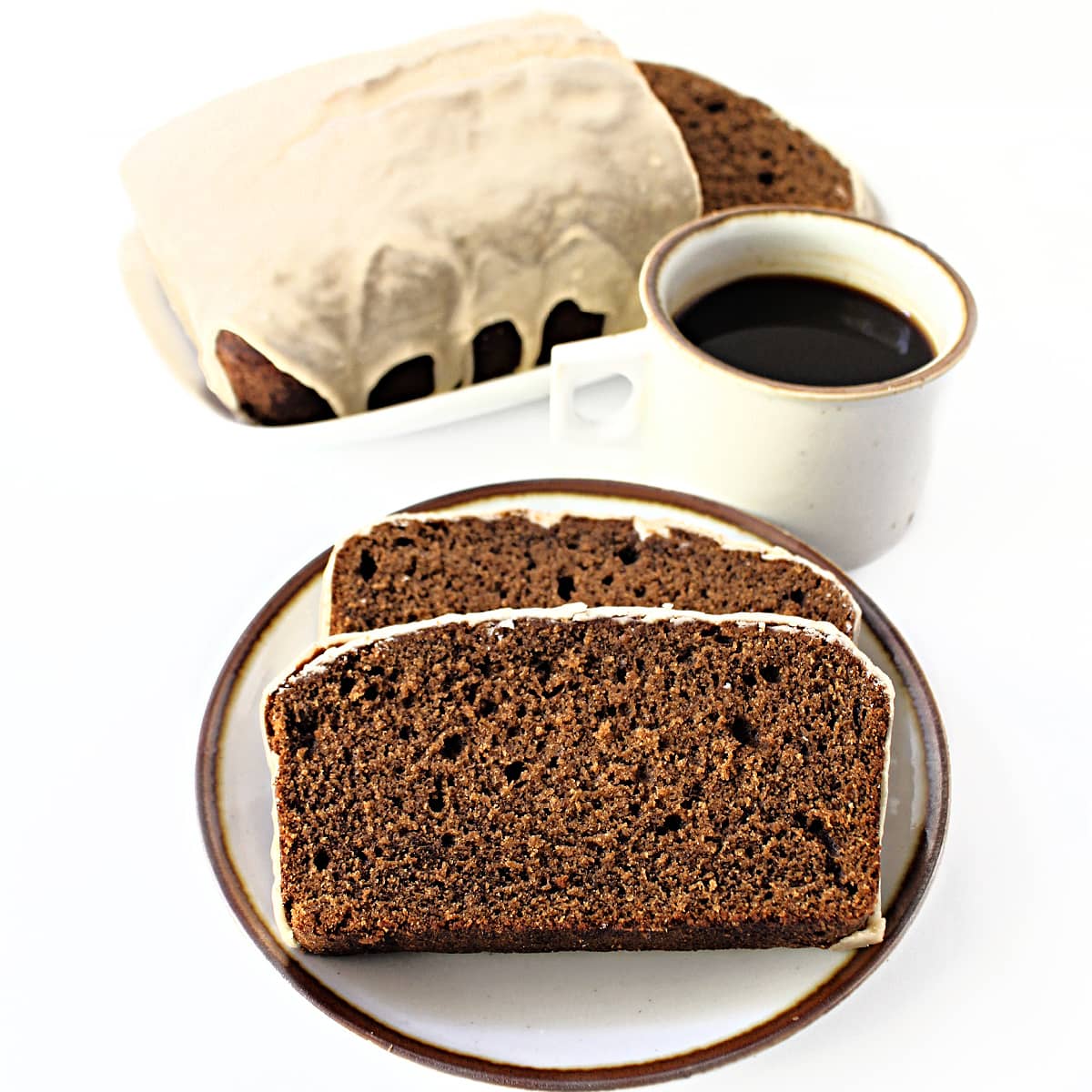 Sliced loaf cake with loaf and coffee mug in the background.