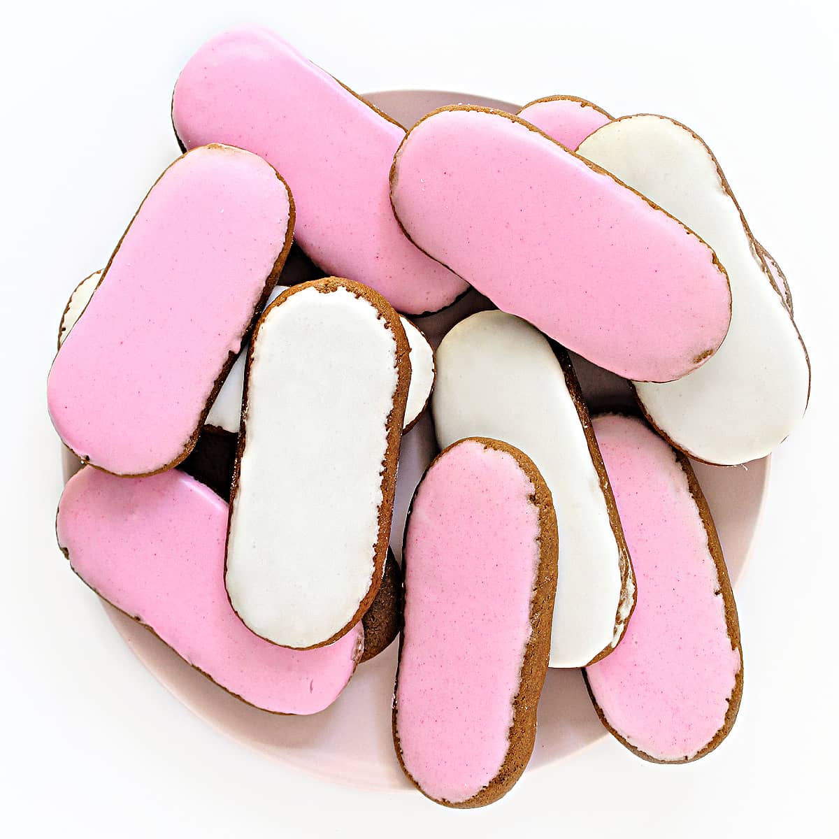 Overhead image of oval pink and white iced cookies on a serving plate.