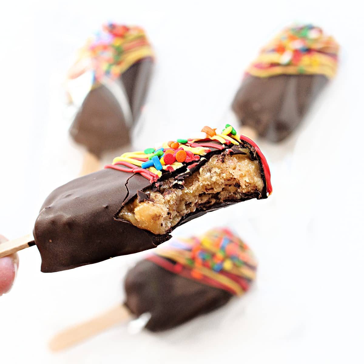 Closeup of chocolate dipped peanut chew pop with a bite taken out to show candy inside.