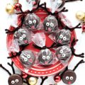 Chocolate covered Christmas Oreos with candy eyes, a red candy nose, and pipe cleaner antlers.