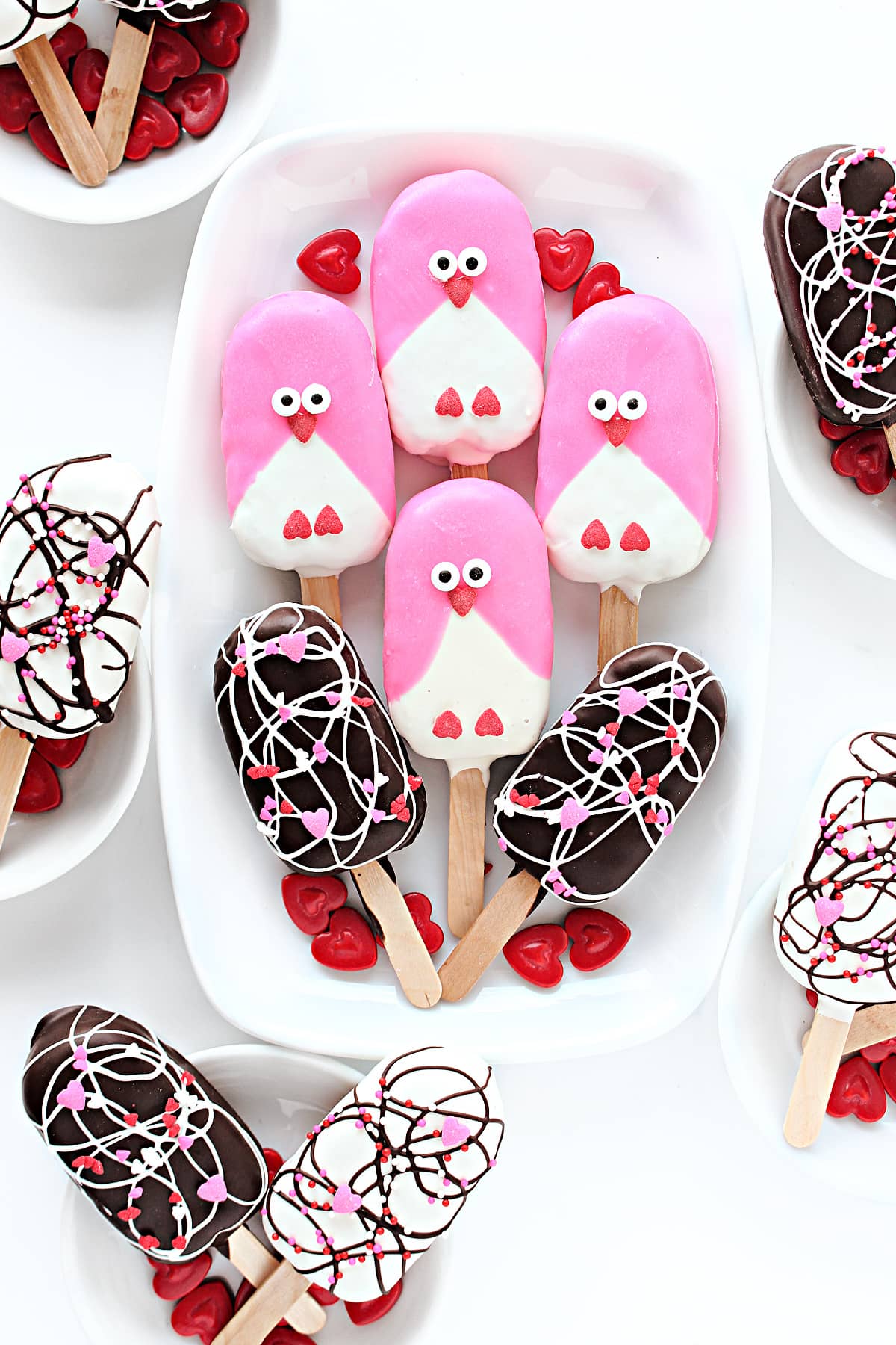 Peanut Chews Pops decorated with candy melts and heart sprinkles in swirls and as love birds.