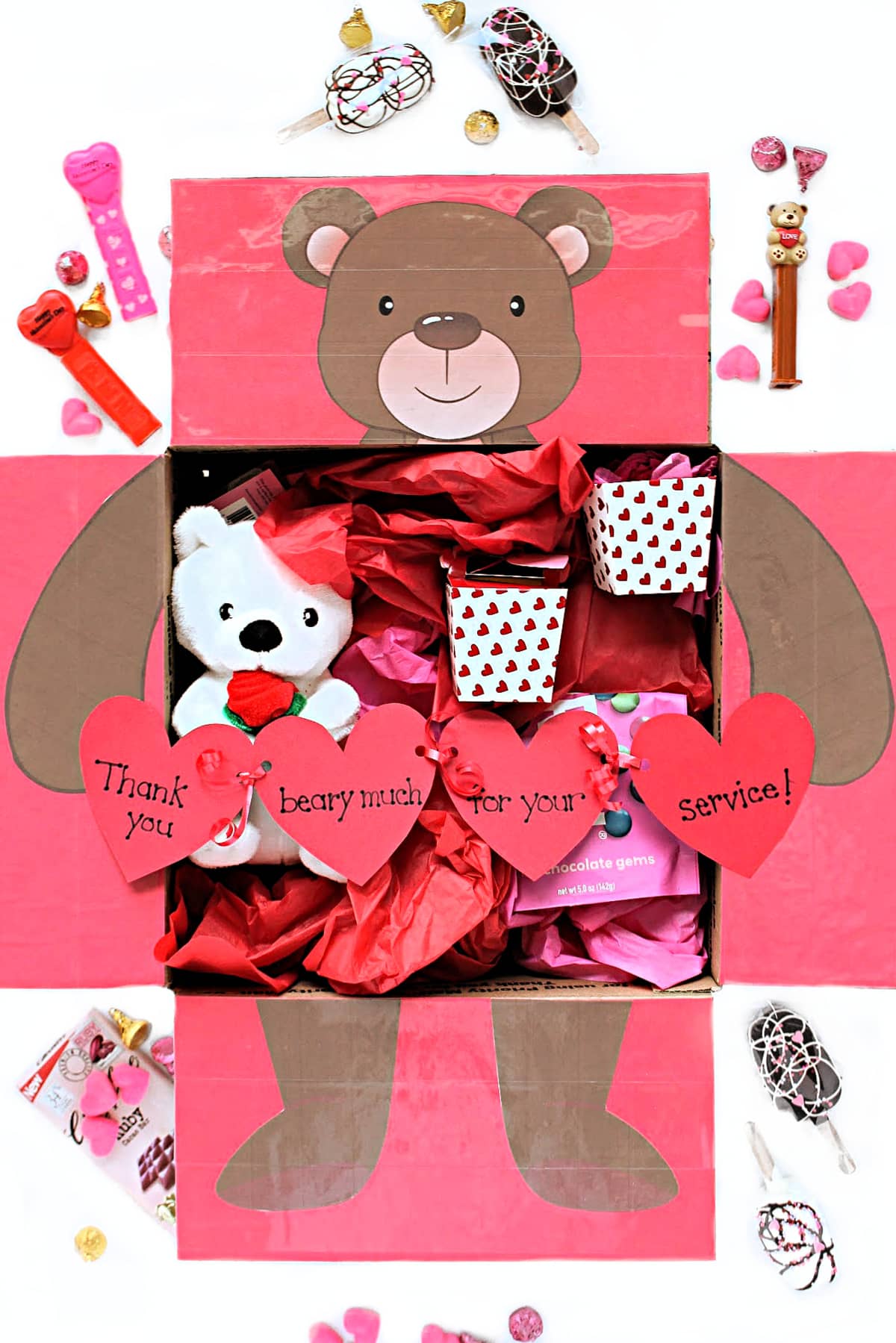 Care package box with flaps decorated with a bear holding a garland of hearts.