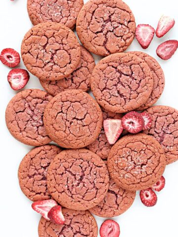 Flat, round, pink cookies with cracks on the top.