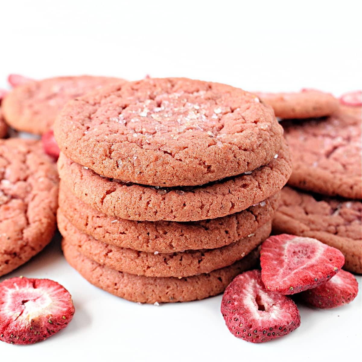 Stack of thin, pink sugar cookies with cracked top and edges.