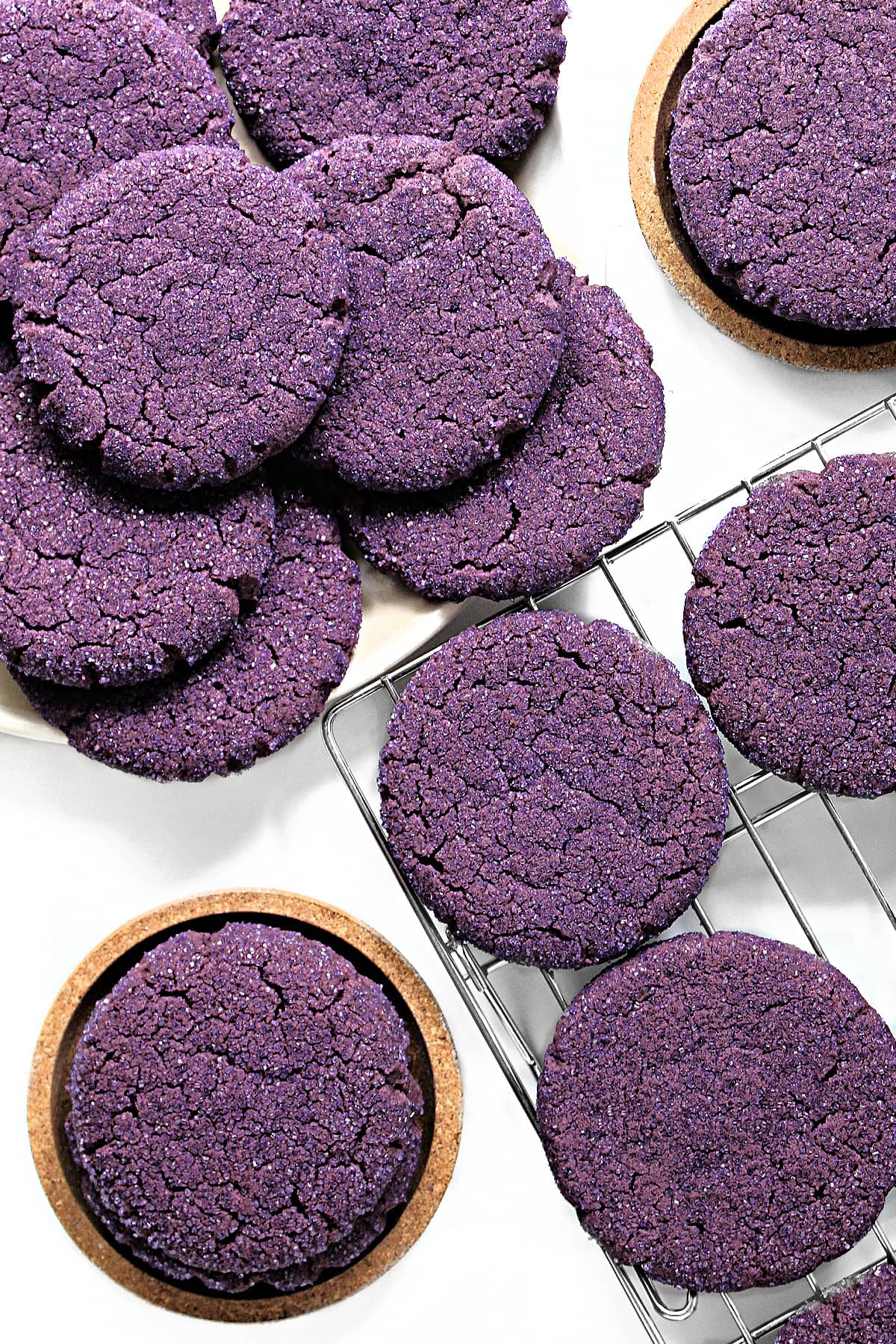 Flat, purple sugar cookies coated in sparkling sugar on a plate and wire cooling rack.