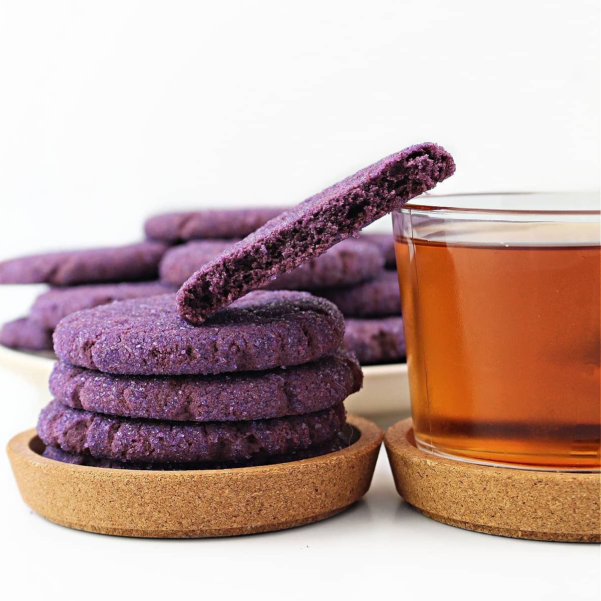 Stack of purple sugar cookies showing thick edge and a cookie half showing interior crumb.