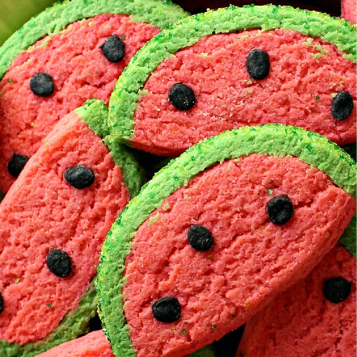 Closeup of Watermelon Sugar Cookies showing the details of the green edge, pink center, and black seeds.