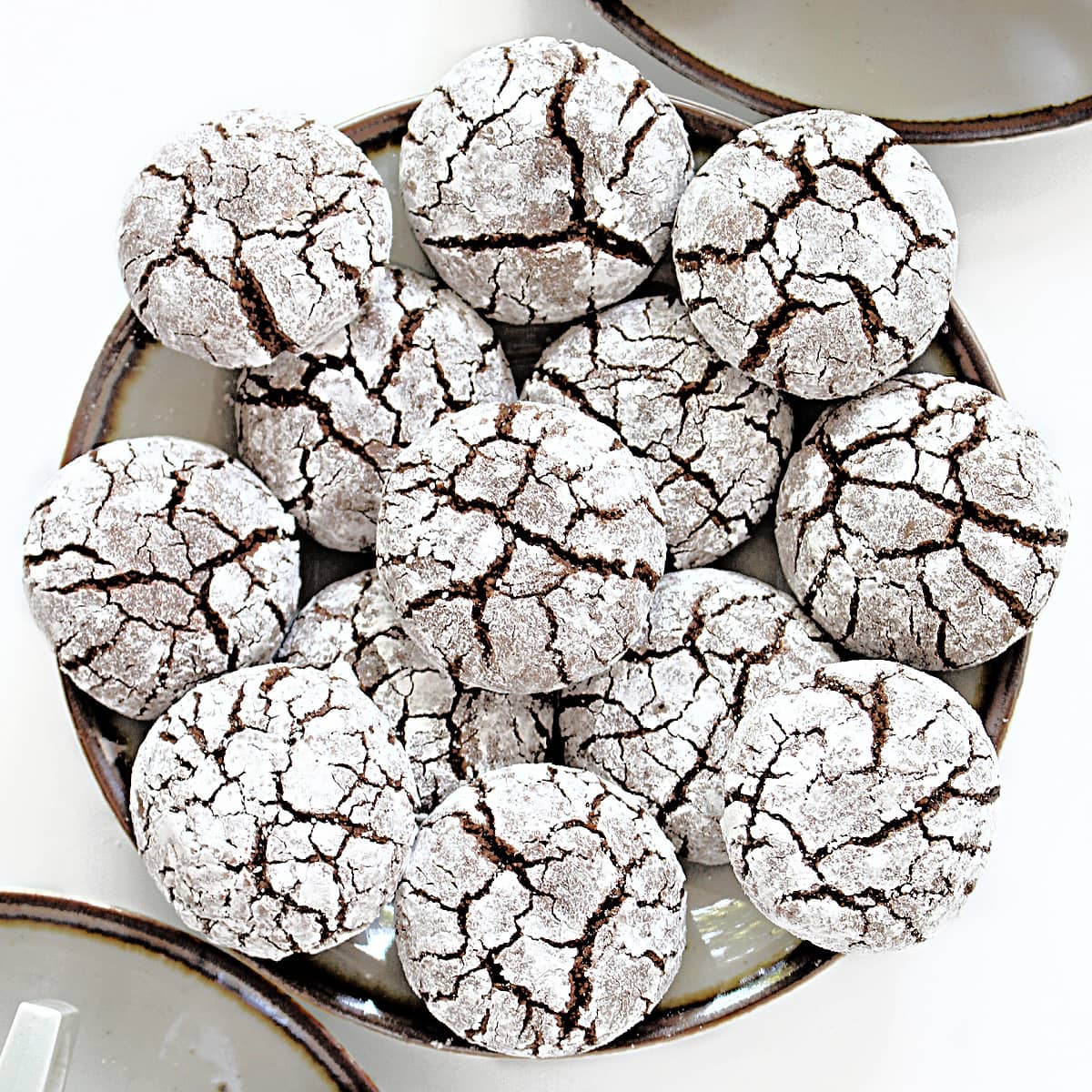 Closeup of cracked tops of powdered sugar covered cookies with chocolate cookie showing through.