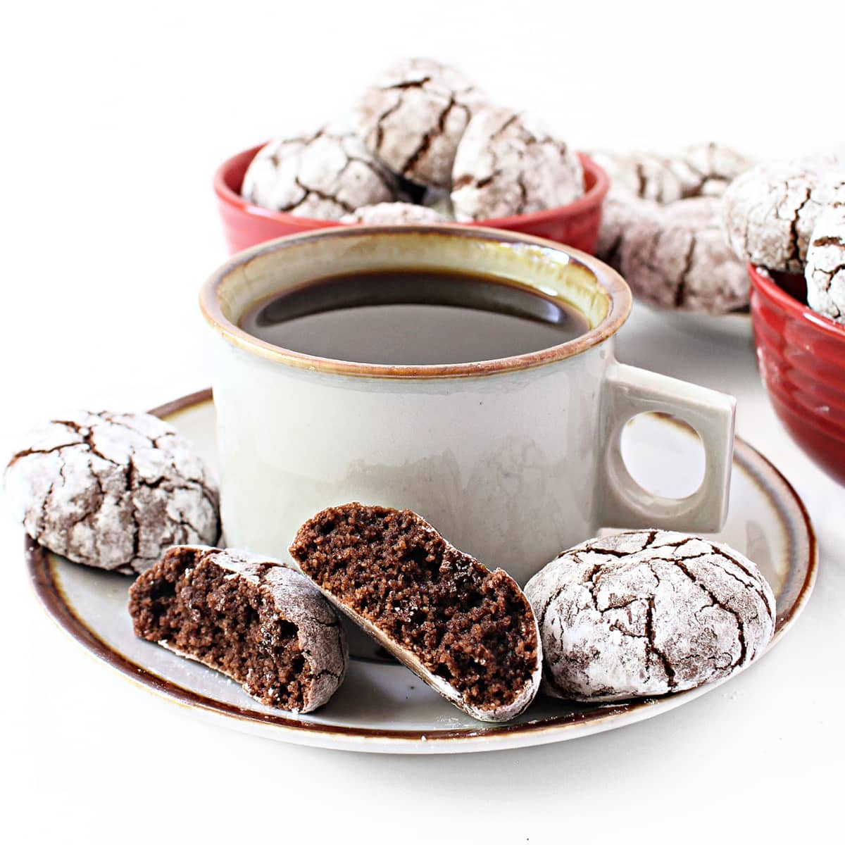 Chocolate cookies, with one split to show soft crumb inside, on a saucer with coffee.