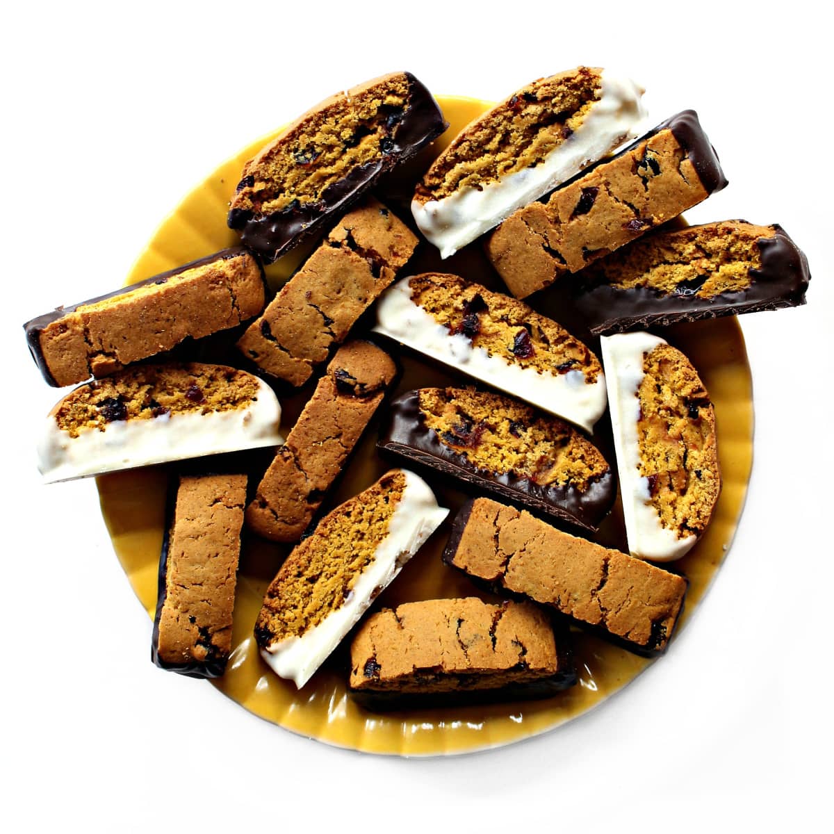 Chocolate dipped Pumpkin Biscotti decoratively arranged on a round, yellow serving platter.