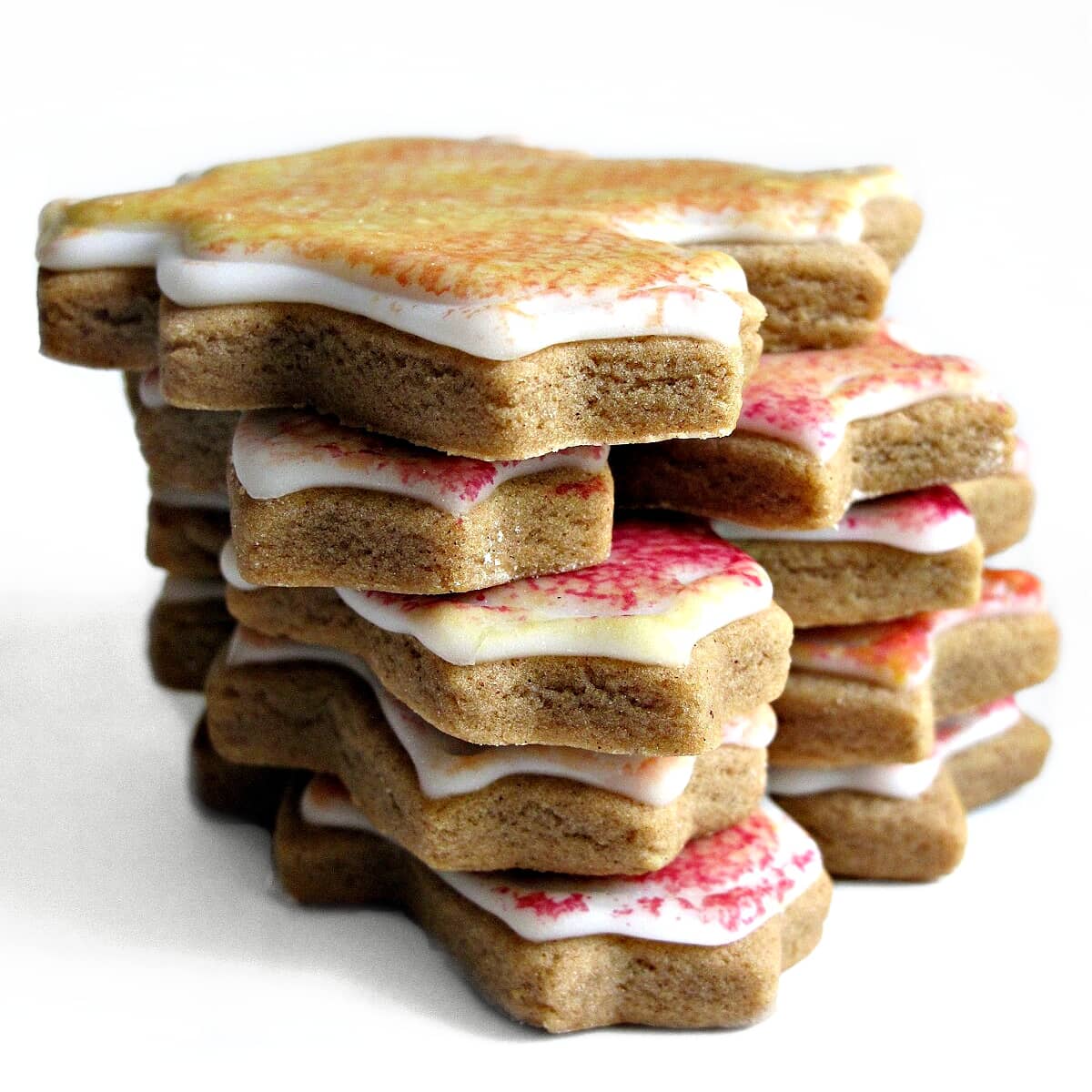 Stack of cutout gingerbread leaf cookies topped with white painted icing.