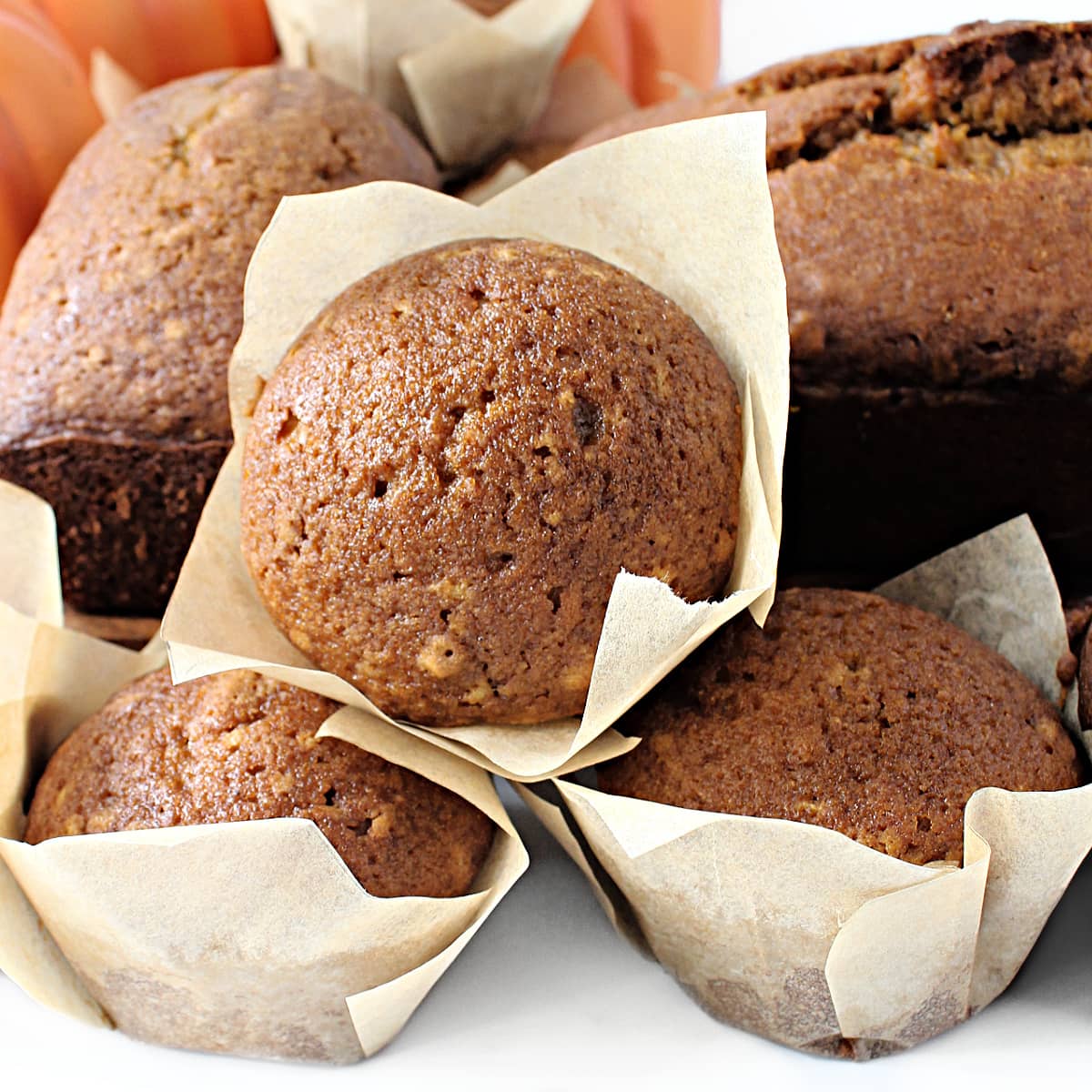 Pumpkin Bread muffins with shiny tops, in tulip paper wrappers.