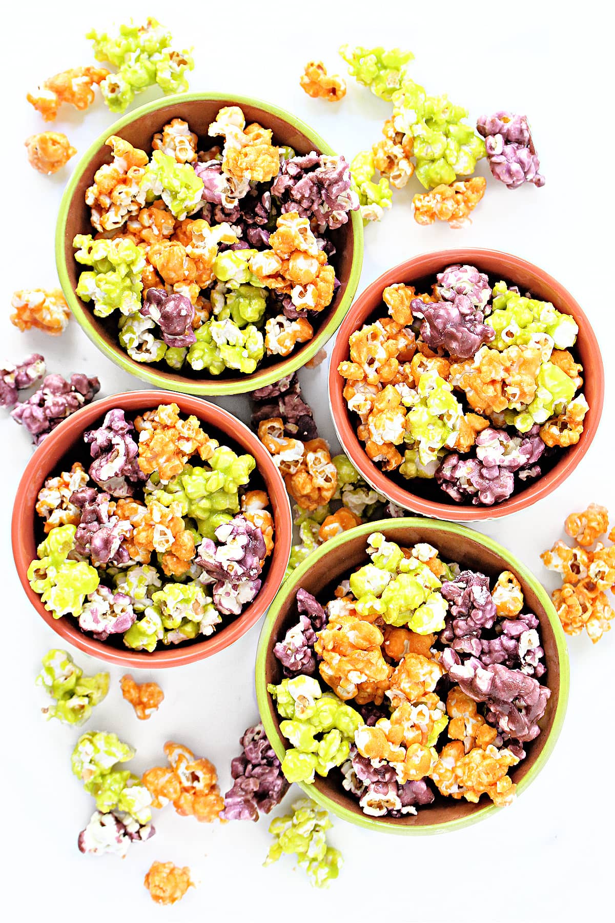 Bowls of candy coated Halloween Popcorn in holiday colors of orange, green, and purple.