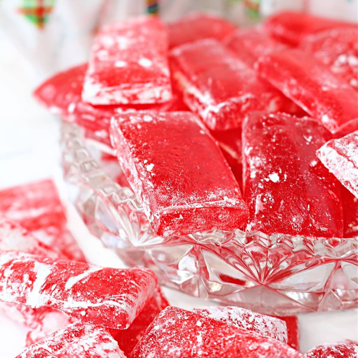 Closeup of transparent red cinnamon hard candy piece dusted with powdered sugar.