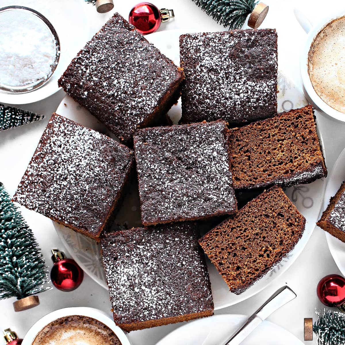 Squares of powdered sugar sprinkled gingerbread cake squares on a plate.