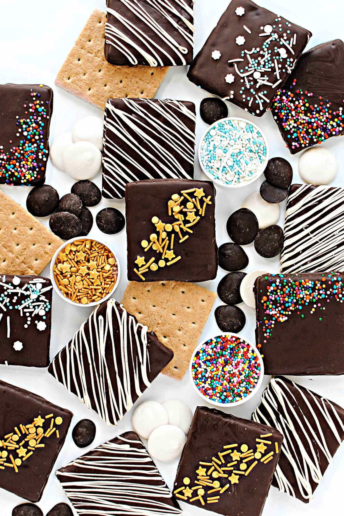 Graham Cracker squares coated in dark chocolate and decorated with sprinkles or white chocolate drizzle.