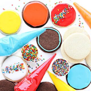 Circle sugar cookies iced with colored glaze with sprinkles and icing bags.