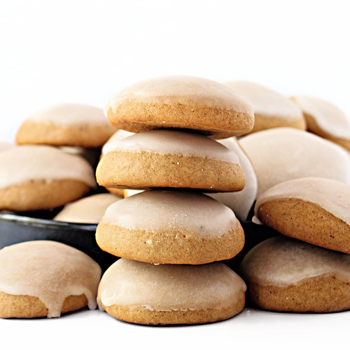 A stack of puffy, rounded Honey Cookies with the domed tops coated in lemon icing.