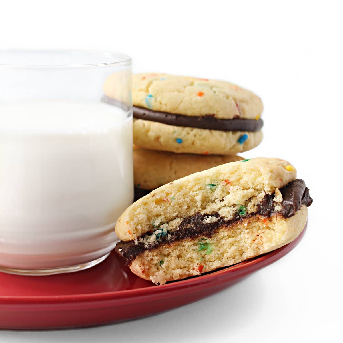 Closeup of a bite taken out of a Funfetti Cake Mix Cookie sandwich cookie with thick, fluffy cookies and chocolate frosting filling.
